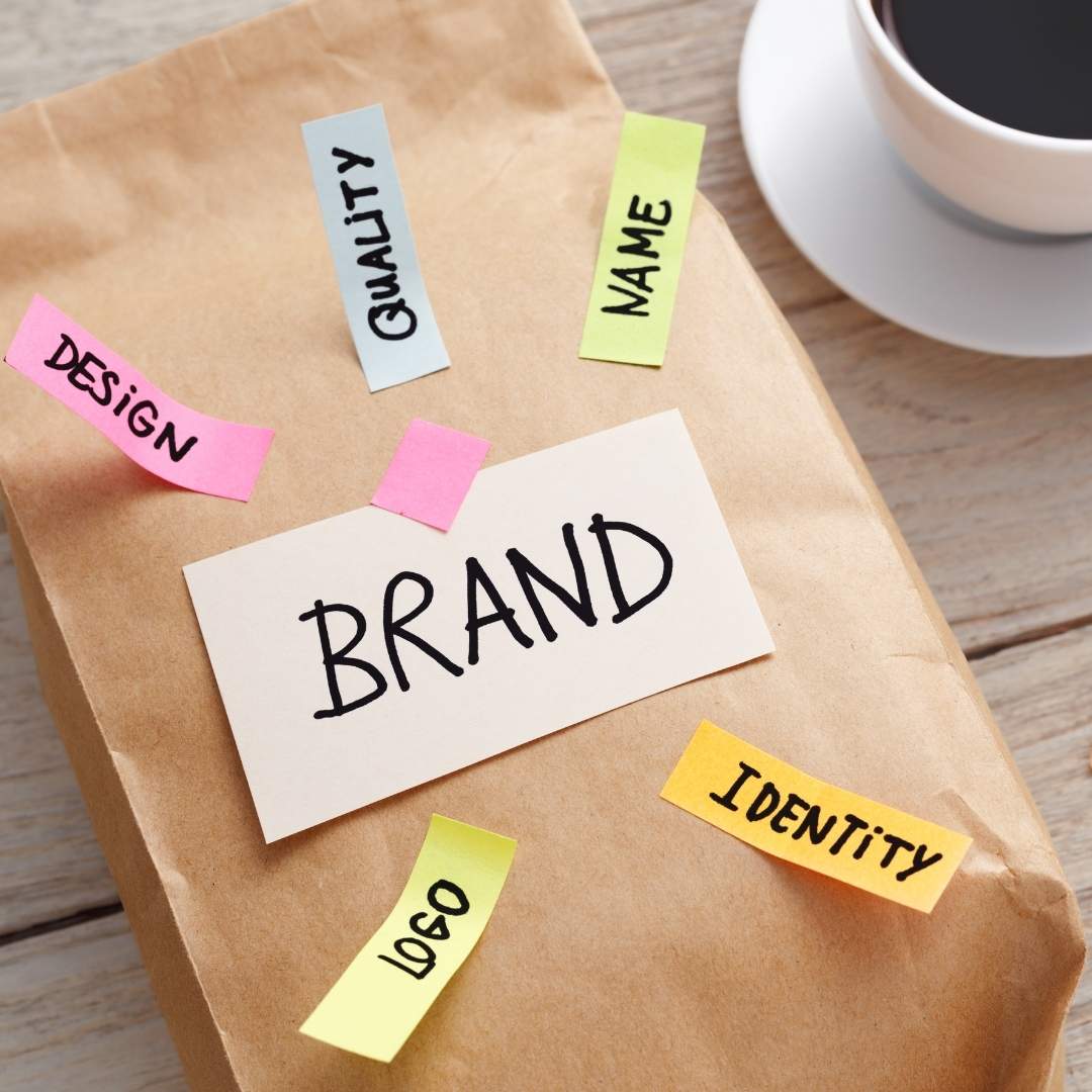 Paper bag with post it tabs that say, Brand, Design, Quality, Name, Identity, and Logo.