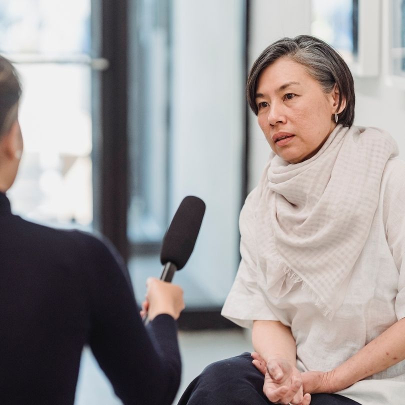 Reporter off screen holding a microphone for a woman who is being interviewed.